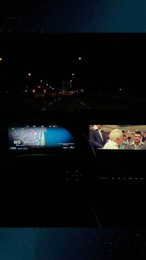Gece araç sürüşü sırasında ön camdan yol görüntüsü ile birlikte multimedya ekranında navigasyon haritası ve yan ekranda film izlenmesi görünüyor.