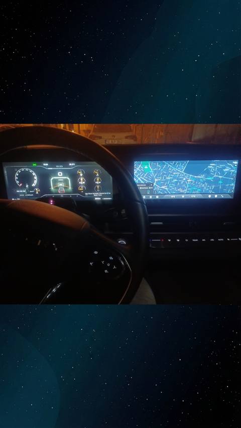 Bir aracin direksiyonu arkasindan dijital gosterge paneli ve navigasyon haritasi ekraninin gece cekilmis fotografi.