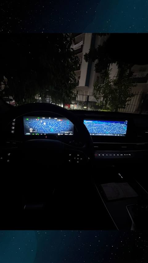 Gece vakti bir aracin ic mekaninda dijital gosterge panelinde ve orta ekranda harita navigasyonu goruntulenmektedir.