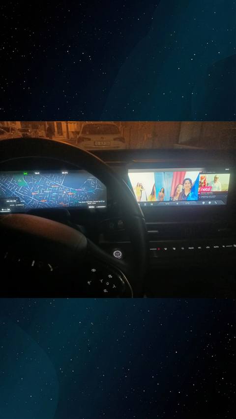 Aracin ic mekanindan gece cekilmis, dijital gosterge panelinde harita/navigasyon ve orta ekranda video/muzik uygulamasinin gorundugu bir fotograf.