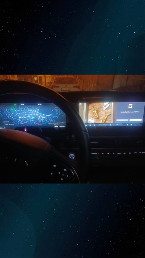 Gece vakti bir araca ait direksiyon, gosterge paneli ve multimedya ekraninda harita navigasyonu goruntulenirken cekilmis bir ic mekan fotografi.
