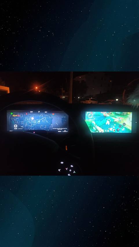 Aracin gece icinden cekilmis, sol ekranda navigasyon haritasi ve sag ekranda bir mobil oyun ekraninin gorundugu multimedya sistemi fotografi.