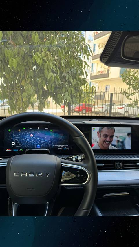 Chery aracin direksiyon arkasindaki dijital gosterge panelinde harita navigasyonu ve orta ekranda video oynatimi gorunmekte.