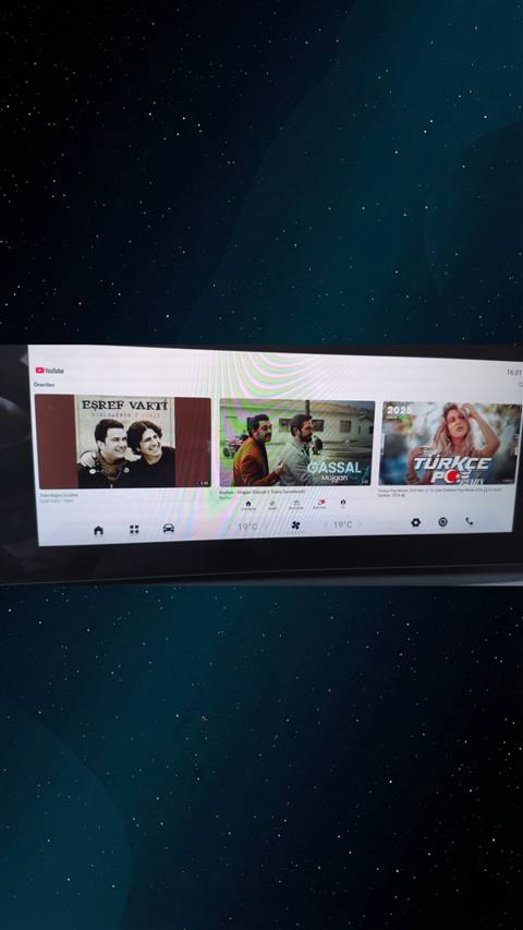 Bir aracin multimedya ekraninda YouTube uygulamasinda onerilen muzik videolarinin goruntulendigi fotograf.