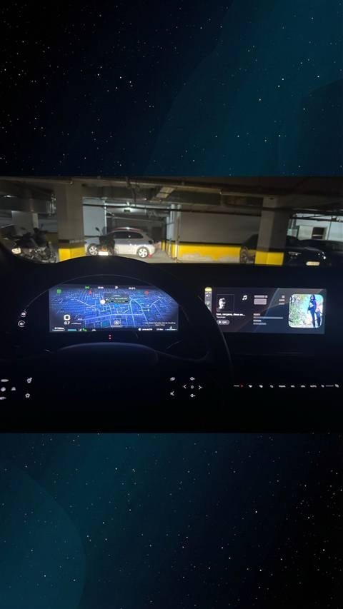 Bir aracin dijital gosterge panelinde navigasyon haritasi ve multimedya ekraninda muzik calar gorunurken arka planda otopark goruntulenmektedir.