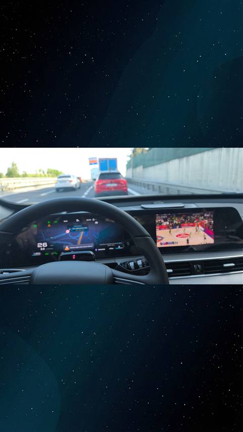 Bir aracin ic mekanindan on cam, direksiyon, dijital gosterge paneli ve multimedya ekraninda navigasyon ile basketbol maci goruntusu yer aliyor.