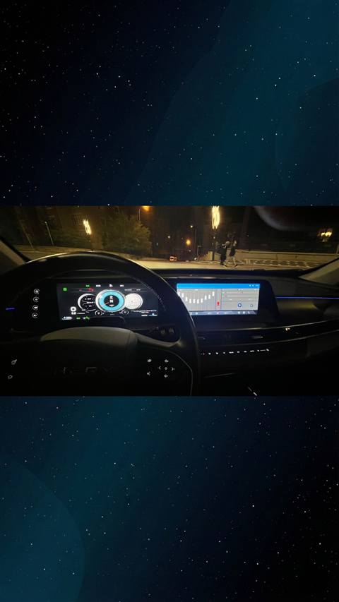 Gece vakti araç içinden dijital gösterge paneli ve multimedya ekranının göründüğü bir fotoğraf.