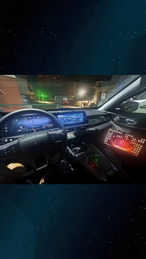 Gece vaktinde bir aracin ic mekani; direksiyon, dijital gosterge paneli, navigasyon ekrani ve renkli LED aydinlatmali konsol gorunmekte.