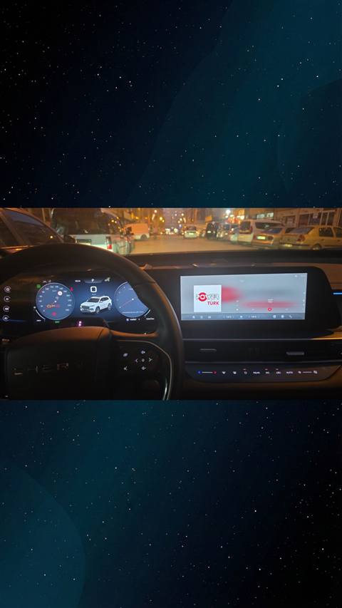 Chery Tiggo aracinin gece sehir trafiginde direksiyon, dijital gosterge paneli ve multimedya ekraninin ic mekan gorunumu.