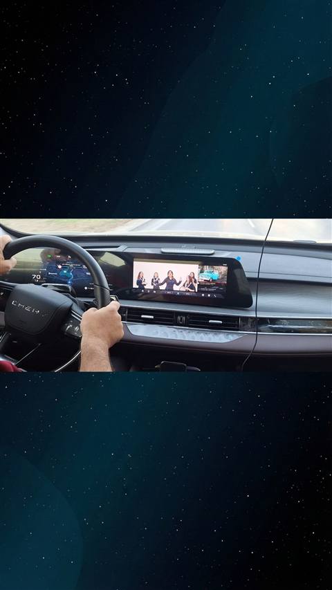 Chery aracin ic mekaninda multimedya ekraninda muzik/video oynatilirken direksiyon basinda bir surucunun eli goruntulenmis.