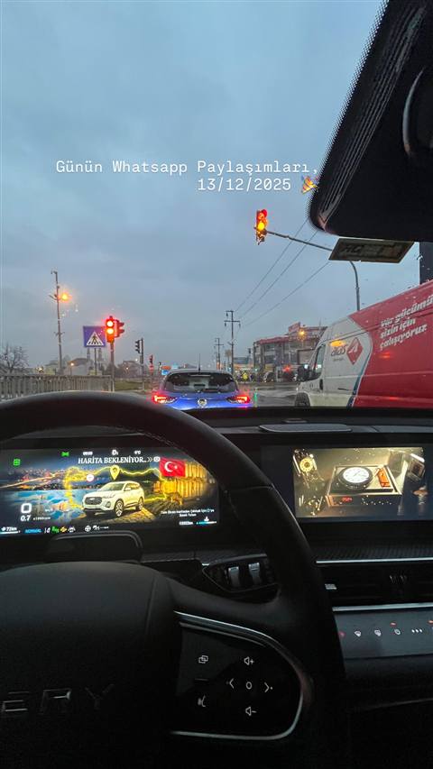 Yagmurlu bir havada trafikte seyir halindeyken arac ici gorunumden navigasyon ekrani, dijital gosterge paneli ve on cam manzarasi gorulmekte.
