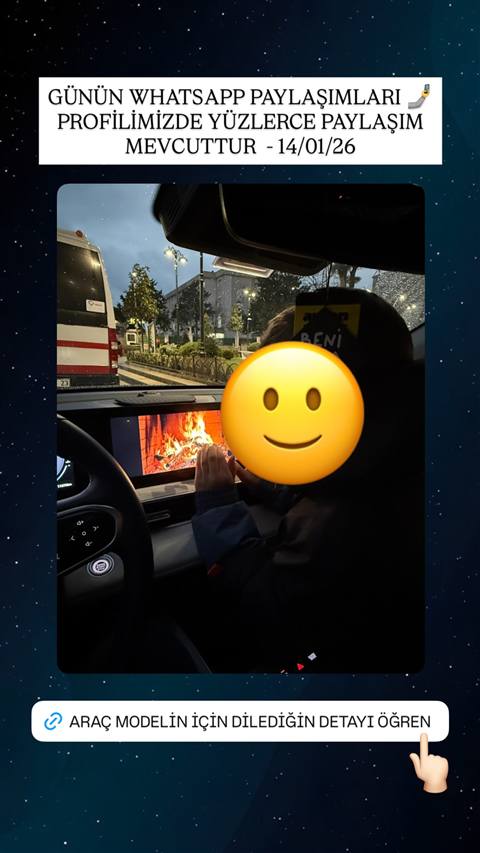 Bir aracin icinden yagmurlu bir aksamda cekilmis, multimedya ekraninda sömine görüntüsü olan ve emoji ile yüzü kapatılmış bir kişinin bulunduğu fotoğraf.