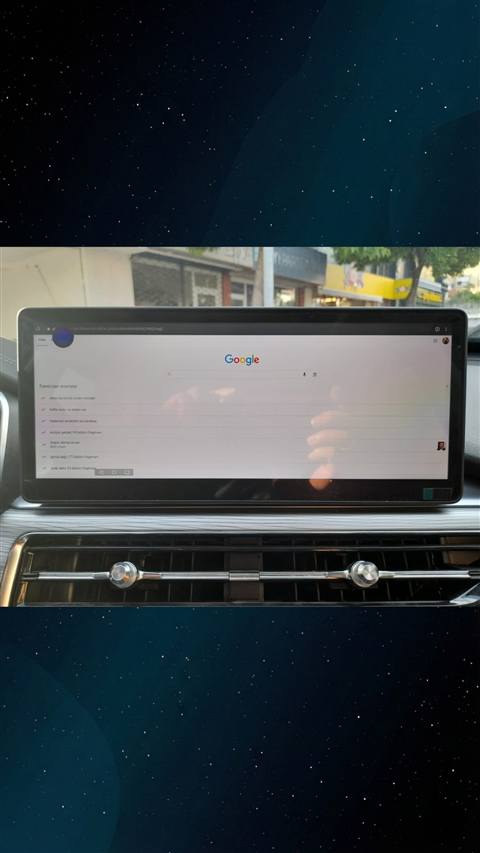 Bir aracın multimedya ekranında Google arama sayfası ve trend aramalar görüntüleniyor, arka planda araç ön camından sokak manzarası görünüyor.