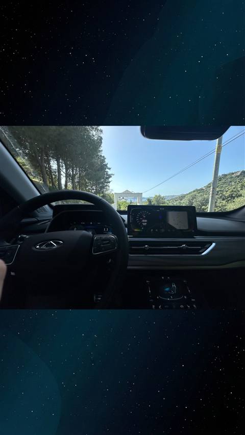 Chery Tiggo aracin icinden direksiyon, dijital gosterge paneli ve multimedya ekrani ile dis manzaranin gorundugu bir fotograf.