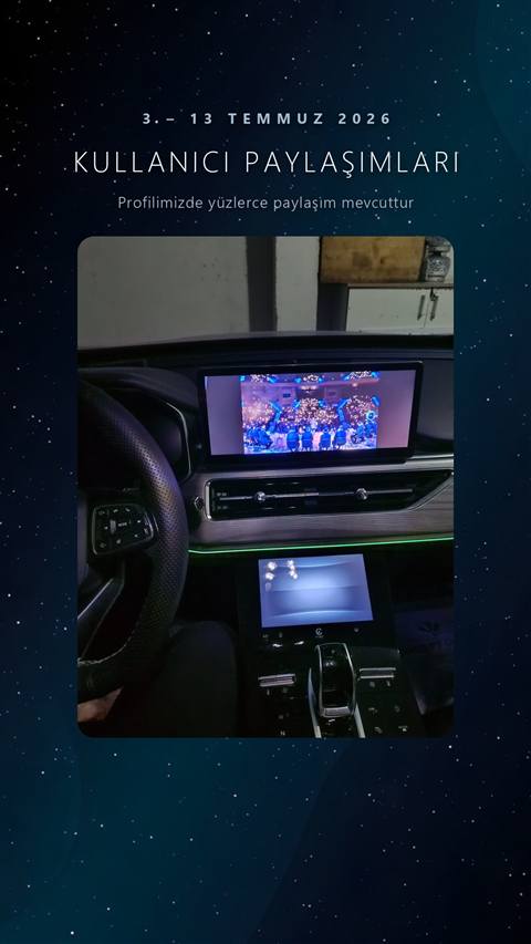 Araç kokpitinden çekilmiş, orta ekranda konser/canlı performans görüntüsü ile alt panelde vites göstergesi görünen bir fotoğraf.